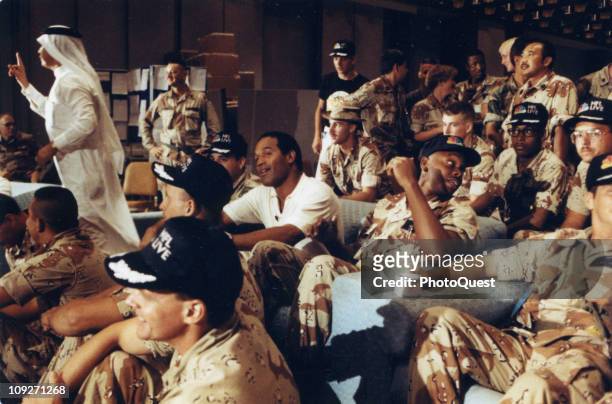 Sports commentator and former professional football player O.J. Simpson, center, watches a Thanksgiving Day football game with United States troops...