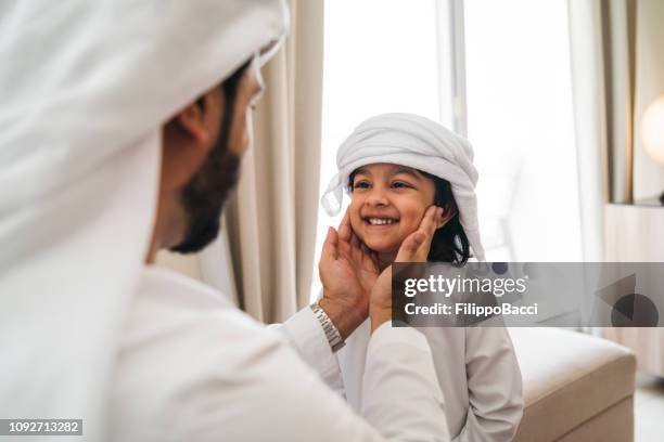 arab man fixing keffiyeh to his son - dubai family stock pictures, royalty-free photos & images