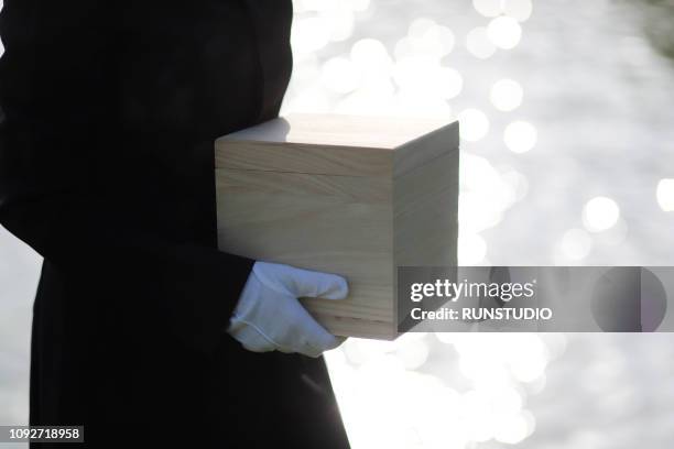 mourner holding urn - crematie stockfoto's en -beelden