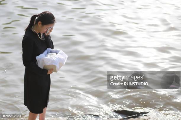 woman grieving with funeral urn - crémation photos et images de collection