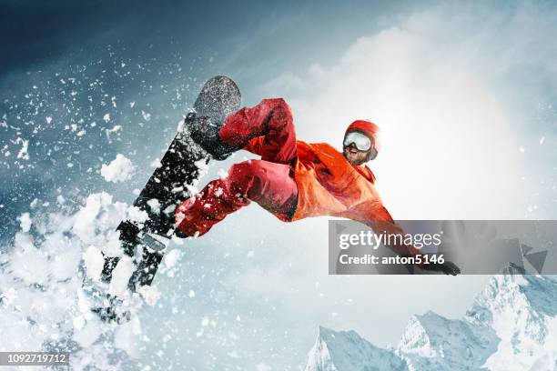 snowboarder salta a través del aire con el cielo azul de fondo - snowboarding fotografías e imágenes de stock