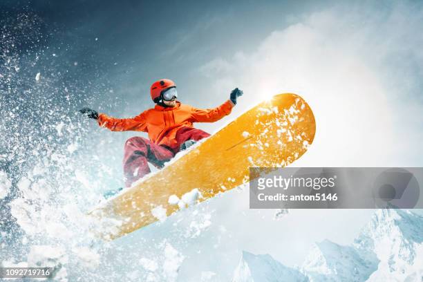 snowboarder jumping through air with deep blue sky in background - snowboarder stock pictures, royalty-free photos & images