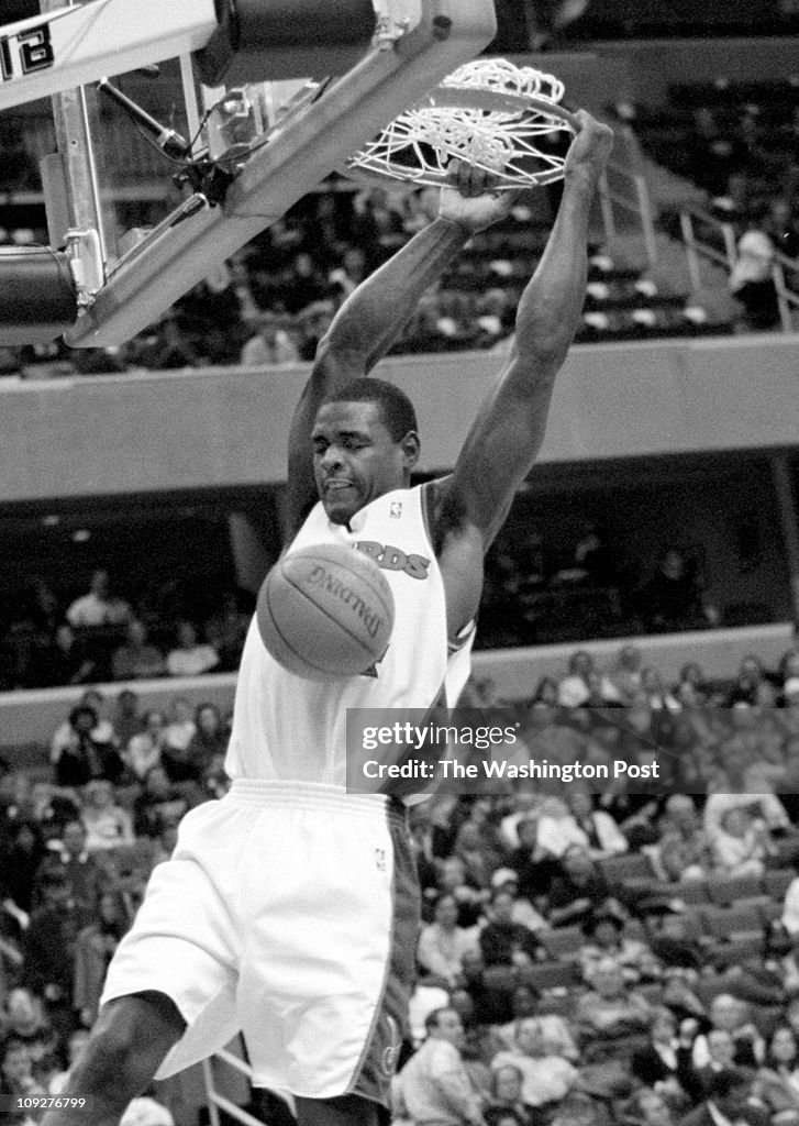 12/17/97 - mci WIZARDS BEAT HEAT - CHRIS WEBBER HANGS ON THE RIM AFTER SLAM DUNK. - Photo By Joel Ri