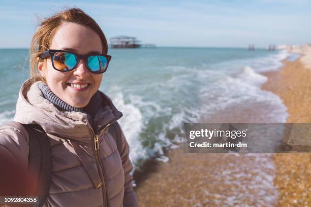 tourist woman taking selfie at the seaside - brighton england stock pictures, royalty-free photos & images