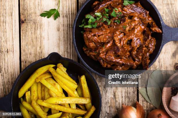 beef stroganoff served with fried potato in cast iron skillet - stoofvlees stockfoto's en -beelden