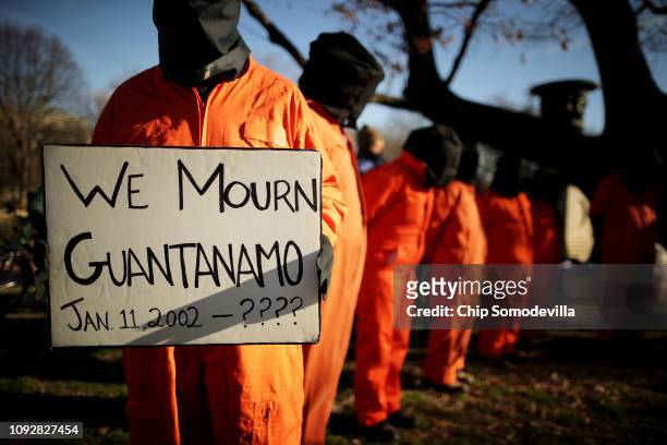 Demonstrators wearing orange jumpsuits and hoods over their heads rally to demand closure of the detention camp at the U.S. Naval Station in...