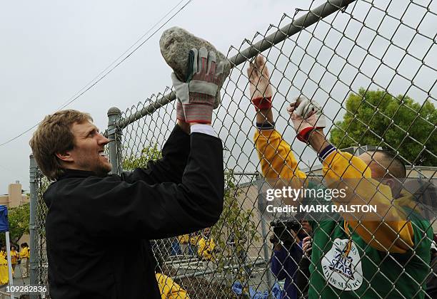 Star Dirk Nowitzki from the Dallas Mavericks, passes a rock as he participates in the "City Year School Refurbishment Project" at the Virgil Middle...