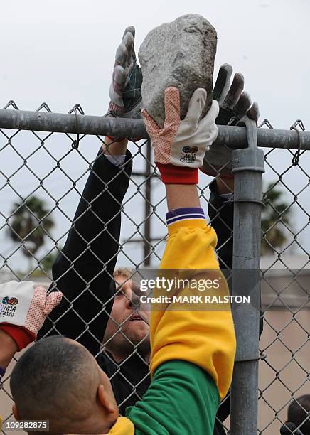 Star Dirk Nowitzki from the Dallas Mavericks, passes a rock as he participates in the "City Year School Refurbishment Project" at the Virgil Middle...