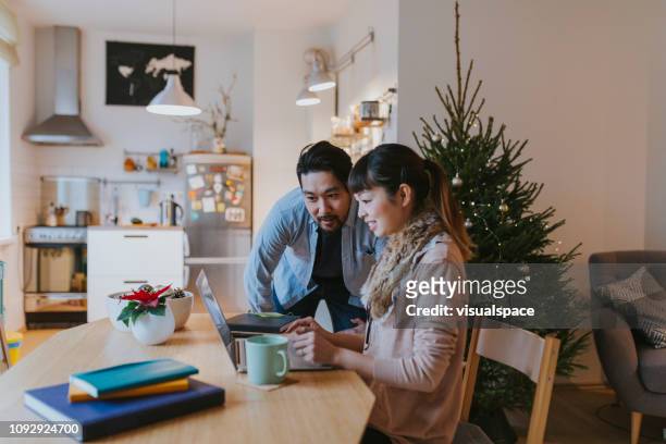japanese man and woman doing christmas online shopping at home - christmas budget stock pictures, royalty-free photos & images