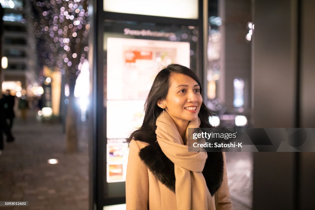 Donna asiatica in cerca del suo negozio preferito in giro per la strada