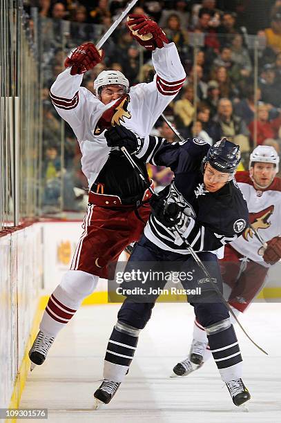 Alexander Sulzer of the Nashville Predators checks Scottie Upshall of the Phoenix Coyotes during an NHL game on February 19, 2011 at Bridgestone...