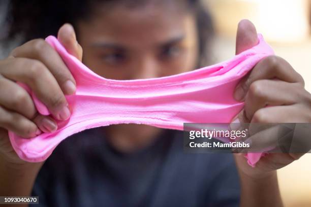 girl is pulling pink clay slime - glitschig stock-fotos und bilder