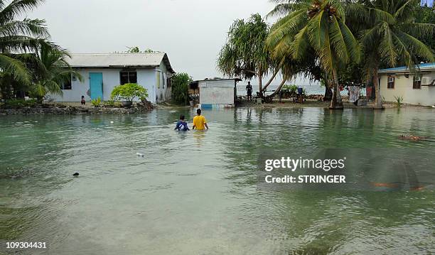 Two local residents wade through flooding caused by high ocean tides in low-lying parts of Majuro Atoll, the capital of the Marshall Islands, on...