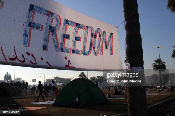 Banner hangs along the Pearl roundabout as protesters awake from spending the night on February 20, 2011 in Manama, Bahrain. The protesters...