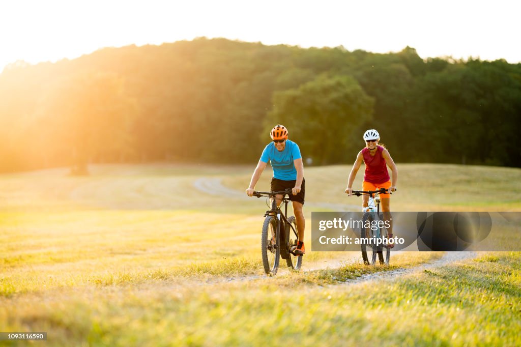Lächelnde sportliches Paar auf Mountain-Bikes in ländlichen Landschaft