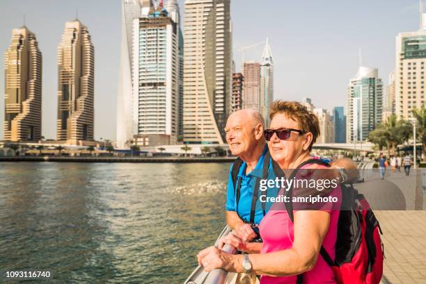 senior couple enjoying view dubai marina on sunny vacation day - couples dubai stock pictures, royalty-free photos & images