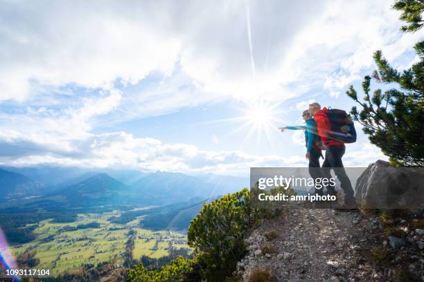 hiking couple viewing mountain range and valley - 40s couple sunny stock pictures, royalty-free photos & images