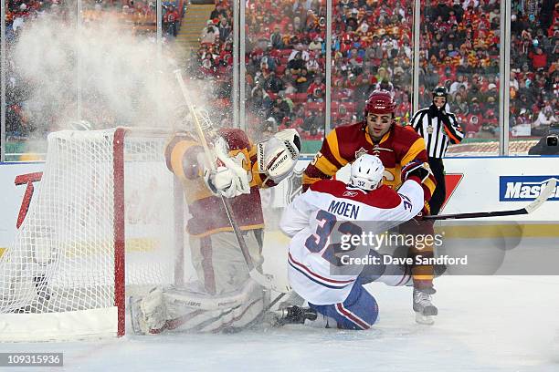 Travis Moen of the Montreal Canadiens slides into the crease area as goaltender Miikka Kiprusoff and Mark Girodano of the Calgary Flames defend the...