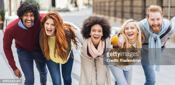 happy friends on the street - community arm in arm stock pictures, royalty-free photos & images