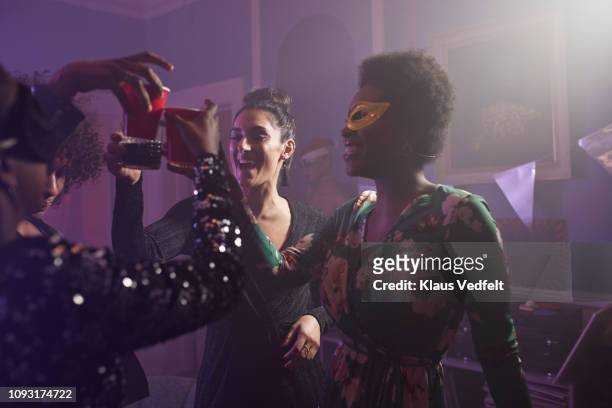 young women dancing and toasting at home party - masquerade mask imagens e fotografias de stock