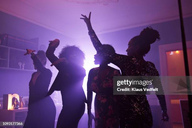 young women dancing and cheering at home party - black room photos et images de collection