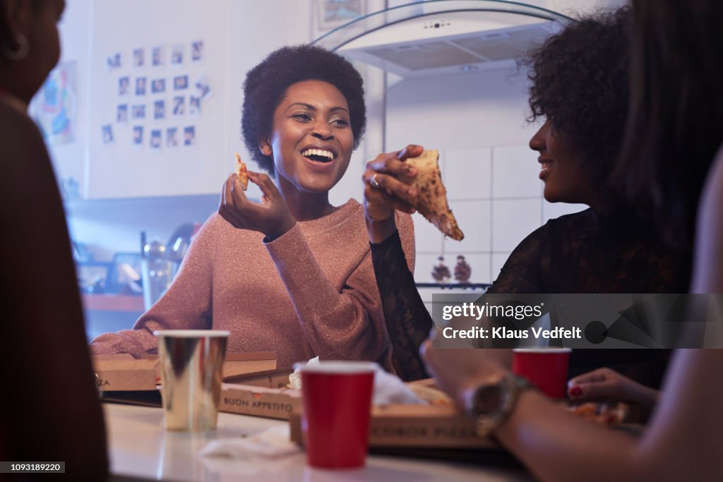 Young women having party in the kitchen and eating pizza
