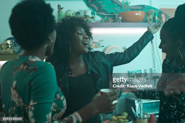 young women laughing and having party in the kitchen - afro hairstyle stock-fotos und bilder