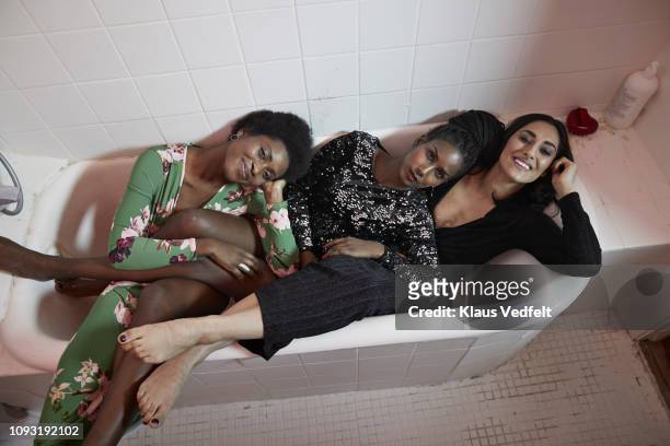 young women relaxing in bathtub at party - black dress party stock-fotos und bilder