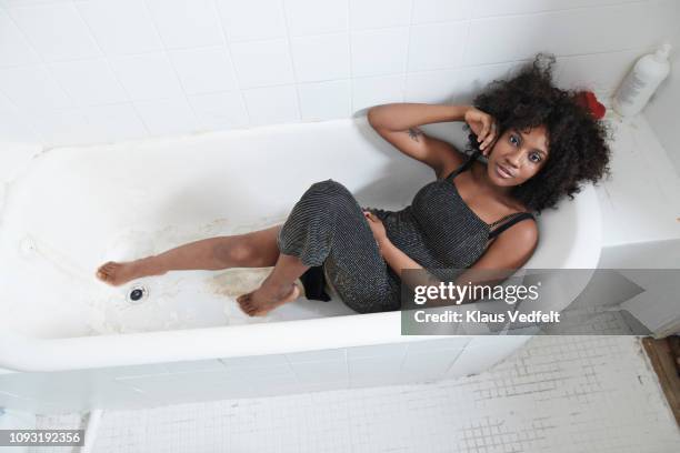 cool young woman laying in bathtub - black jumpsuit stock pictures, royalty-free photos & images