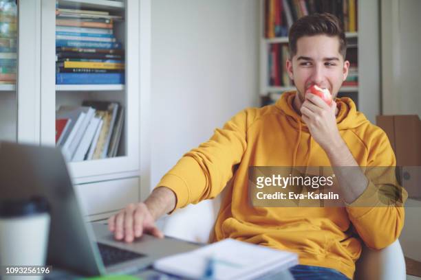 young man working at home - eat apple stock pictures, royalty-free photos & images