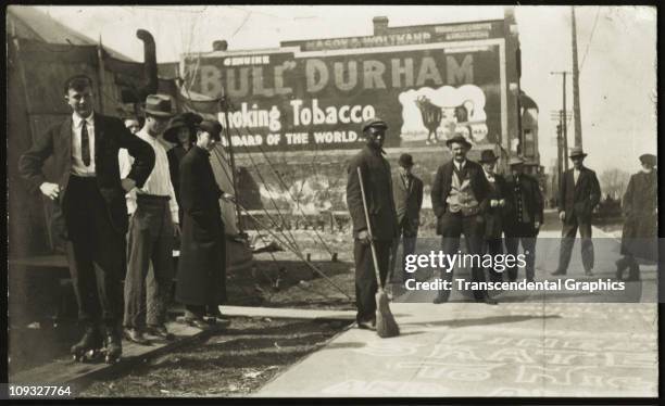 Circa 1910, Street scene with an uneasy feeling, in an unknown south eastern city in the US where a group has gathered to watch roller skating on the...