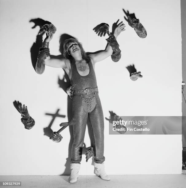 Ozzy Osbourne posed in a studio wearing a codpiece being attacked from behind by arms in leather gloves.