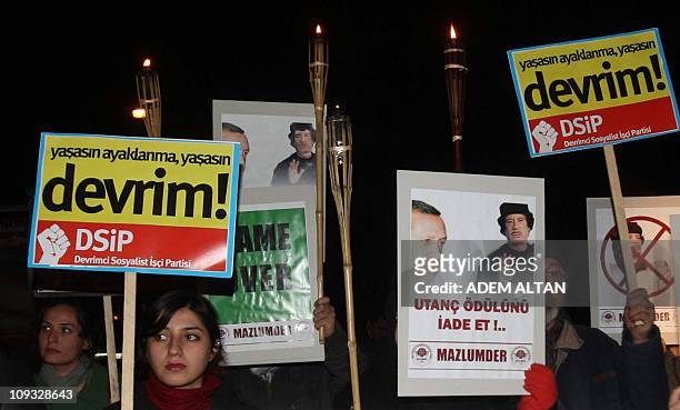 Members of a group of a pro-Islamic human rights activists stand behind banners featuring Libyan leader Moamer Kadhafi and Turkish Prime Minister...
