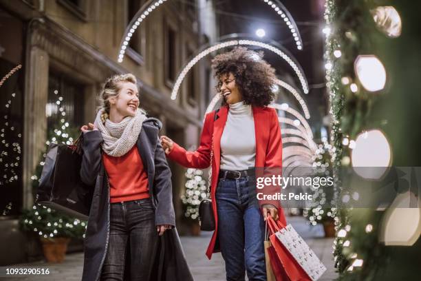 twee aantrekkelijke jonge vrouwen in het winkelen van kerstmis - women's winter clothes stockfoto's en -beelden