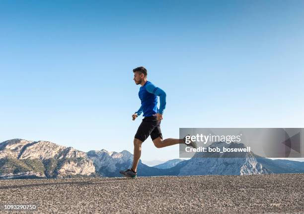 sportsman running on asphalt road - endurance run stock pictures, royalty-free photos & images