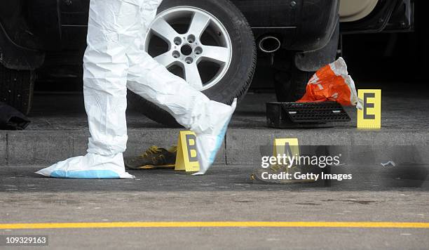 Police forensic officer walks by a pair of shoes beside a car that crashed into in the departure terminal of Malpensa Airport on February 21, 2011 in...
