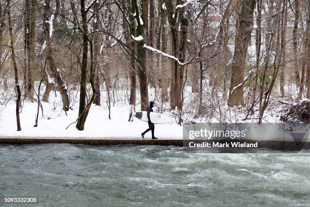 Surfer walks along the Eisbach wave in the English Garden on January 12, 2019 in Munich, Germany. The Eisbach, wave is a man-made wave in the river...