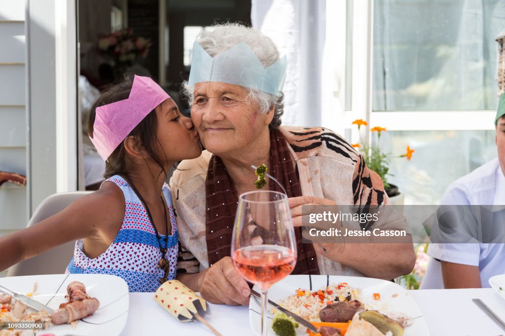 Girl kisses grandma at outdoor Christmas lunch