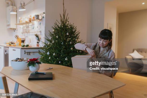 happy japanese woman receives parcel during christmas - package arrival stock pictures, royalty-free photos & images
