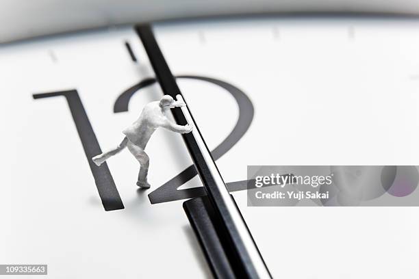 clock with a toy  sized human - clock hand stock pictures, royalty-free photos & images