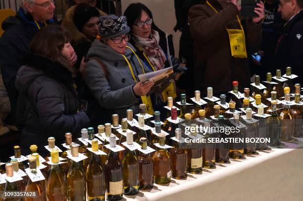 People look at wine bottles before an auction during the traditional event of the "Percee du vin jaune" in Poligny, eastern France on February 2,...