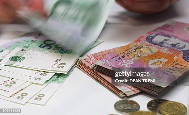 Currency exchange teller counts out Chinese Yuan alongside a stack of New Zealand dollars in Auckland, 21 April 2007. The New Zealand dollar hit...