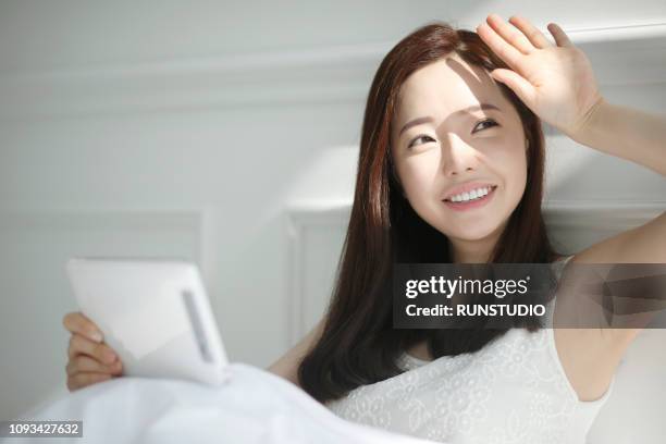 young woman with digital tablet on bed - beautiful people ストックフォトと画像