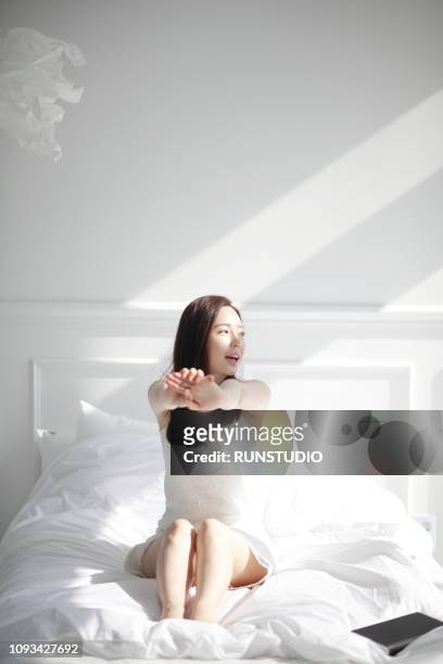young woman smiling and stretching in bed - good morning ストックフォトと画像