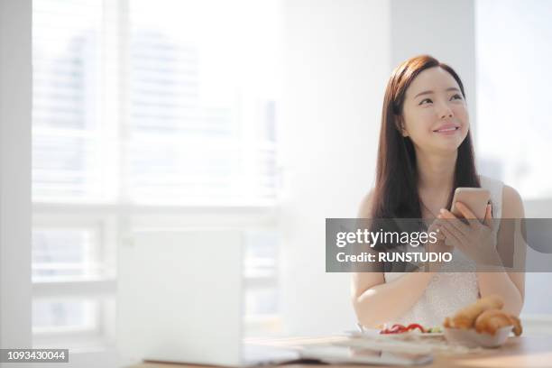 young woman using smartphone at home - 女性　部屋 ストックフォトと画像