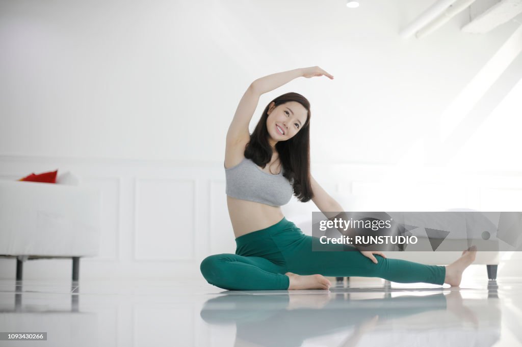 Young woman practicing yoga in bedroom