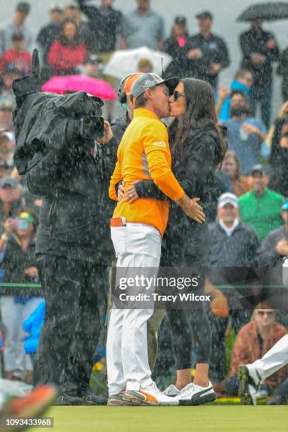 Rickie Fowler shares a kiss in the pouring rain with his fiancé' Allison Stokke after winning the Waste Management Phoenix Open at TPC Scottsdale on...