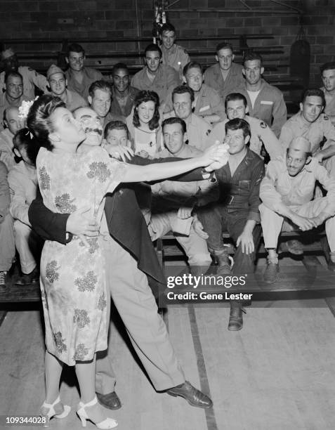 American comedian and actor Groucho Marx dances wth Dorothy Lamour at March Airforce Base for the amusement of the airmen on bleachers behinds them,...