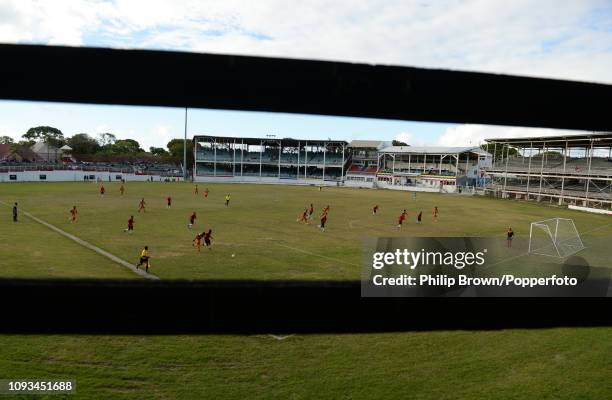 Footall match between Aston Villa and Sandals INET Grenades is seen through a hole in the cricket scoreboard on the day after the West Indies won the...
