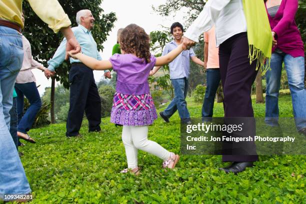 hispanic family holding hands in a circle outdoors - young woman and senior lady in a park stock pictures, royalty-free photos & images